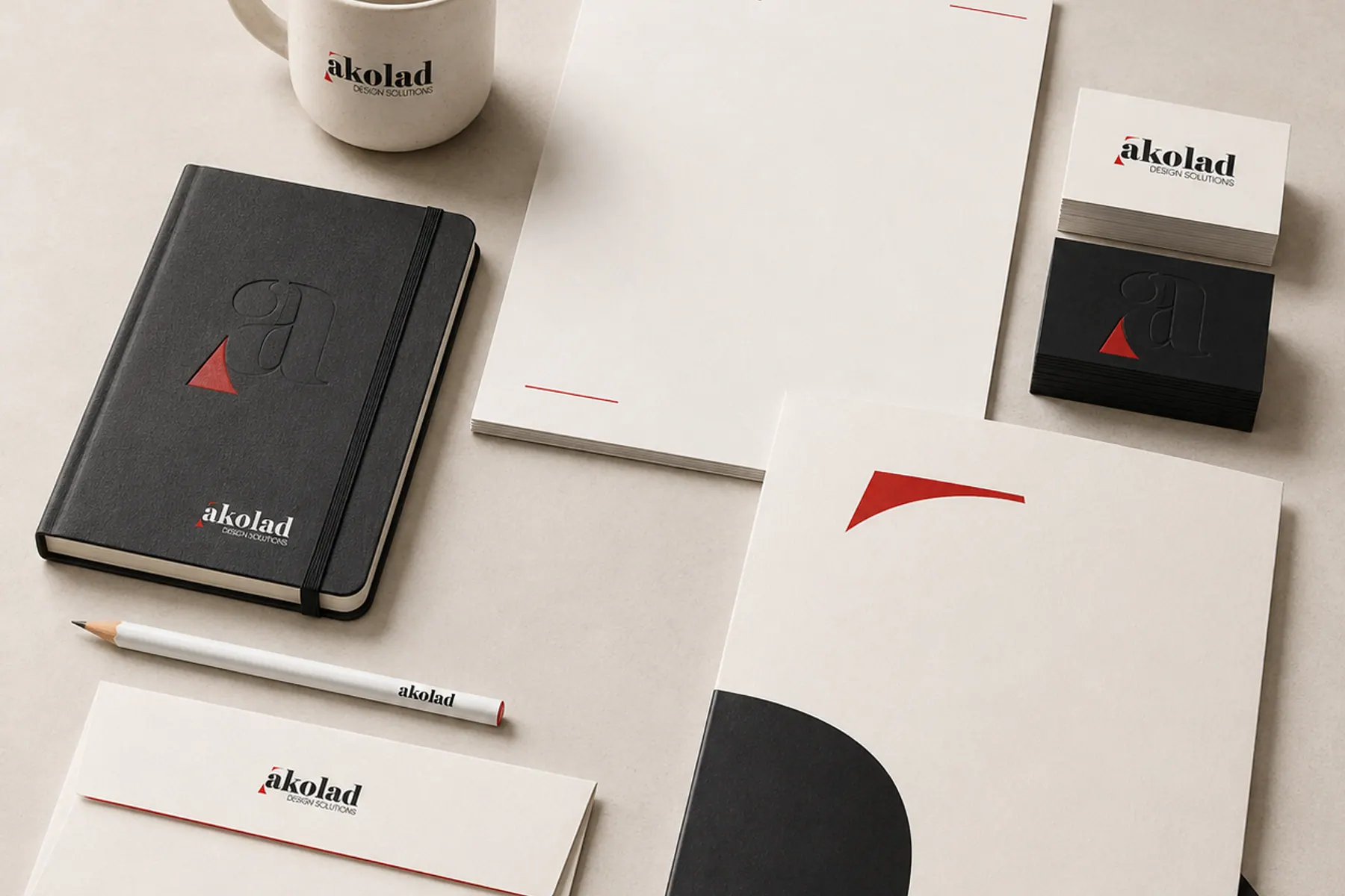 Stationery suite laid out on a warm grey surface: letterhead, business cards, envelope, folder and notebook.