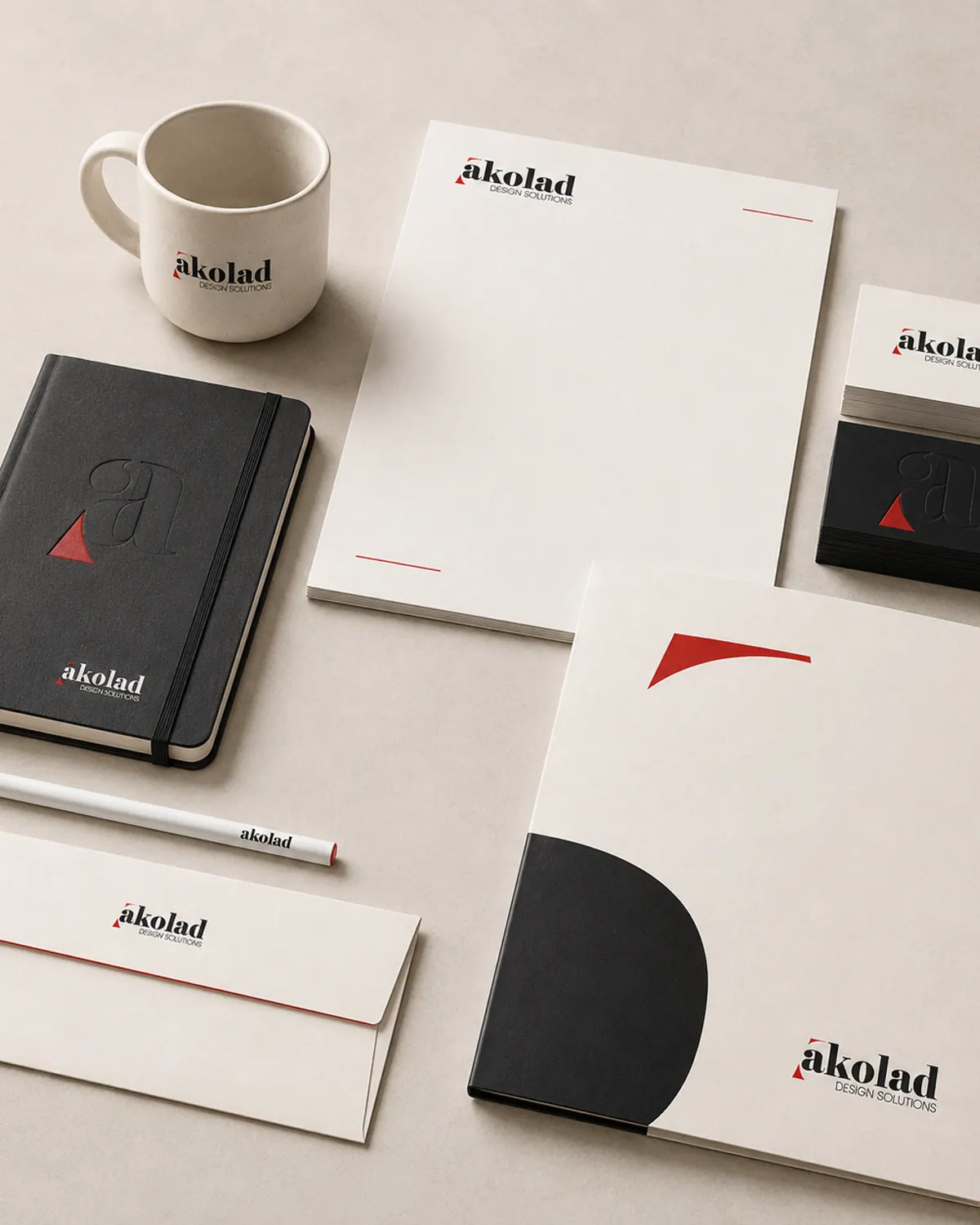 Stationery suite laid out on a warm grey surface: letterhead, business cards, envelope, folder and notebook.
